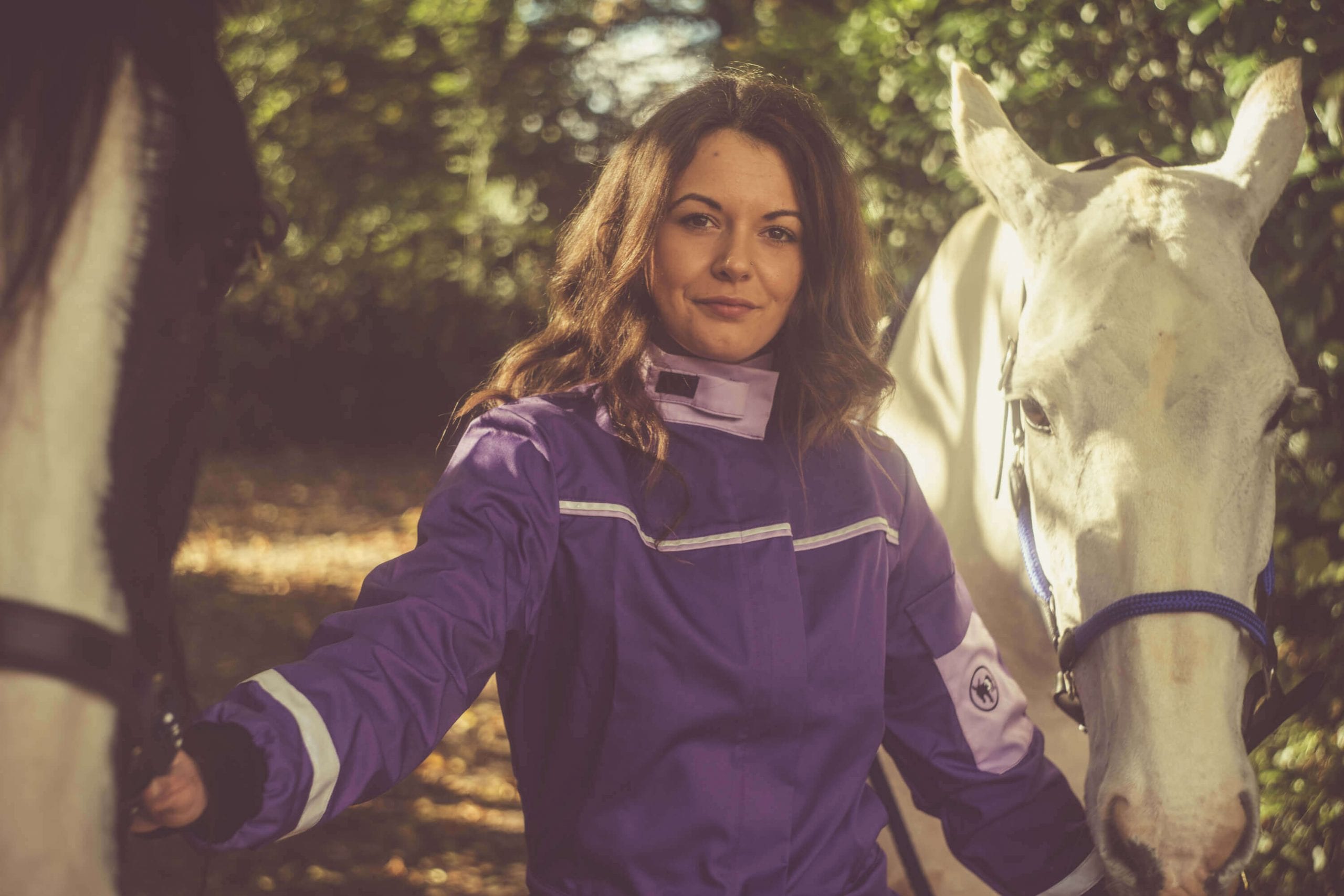 woman-in-purple-coverall-holding-a-horse-and-a-white-horse-on-its-side