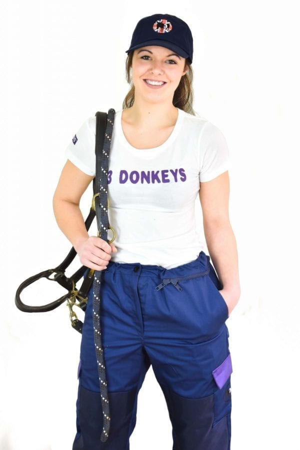 a girl wearing white t-shirt and blue coverall with a climbing harness