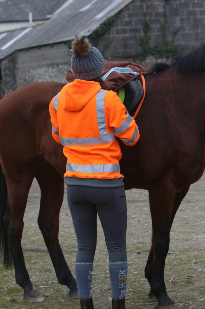 Woman wearing a 3 Donkeys hi-vis Foxworthy hoodie standing next to a horse